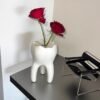 Interesante jarrón con forma de diente que se puede utilizar para arreglos florales como portavelas o para el hogar